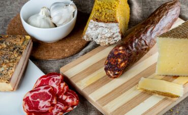 Closeup shot of a piece of parmesan cheese Ventricina sausage and bread on a cutting board A closeup shot of a piece of parmesan cheese Ventricina sausage and bread on a cutting board